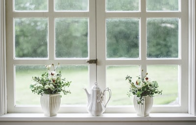 窗玻璃上的白色茶壶和两个花瓶